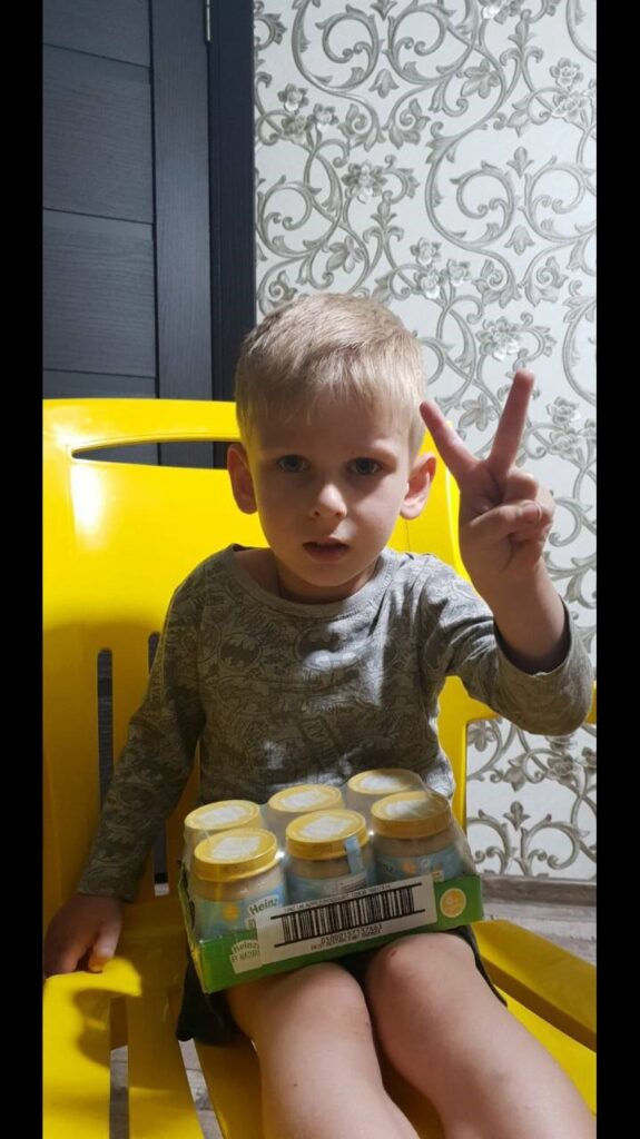 Boy receives supplies and gives a peace sign to camera.