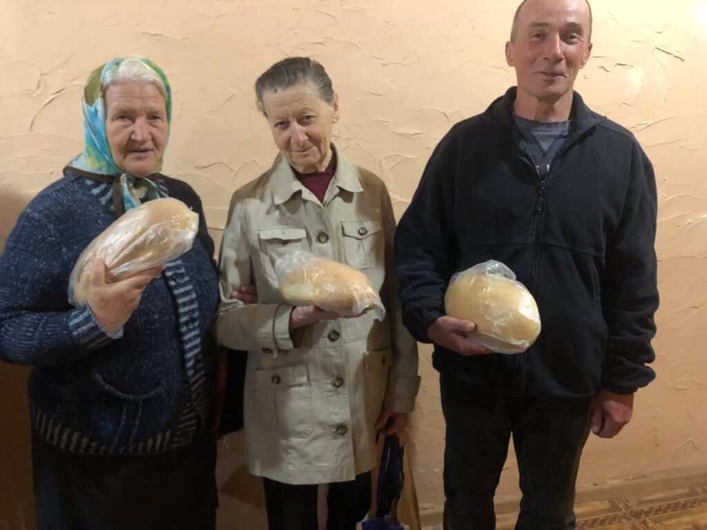 Man and two women receive bread.