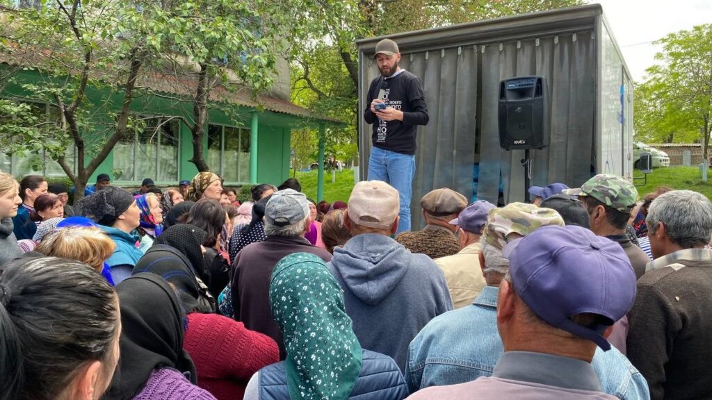 Men sharing to a crowd of Ukrainians.