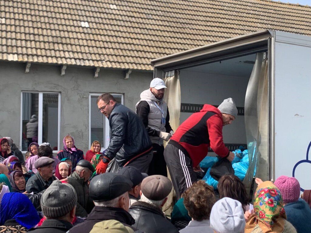 Ukrainian team distributing hygiene supplies to a crowd of needy people.