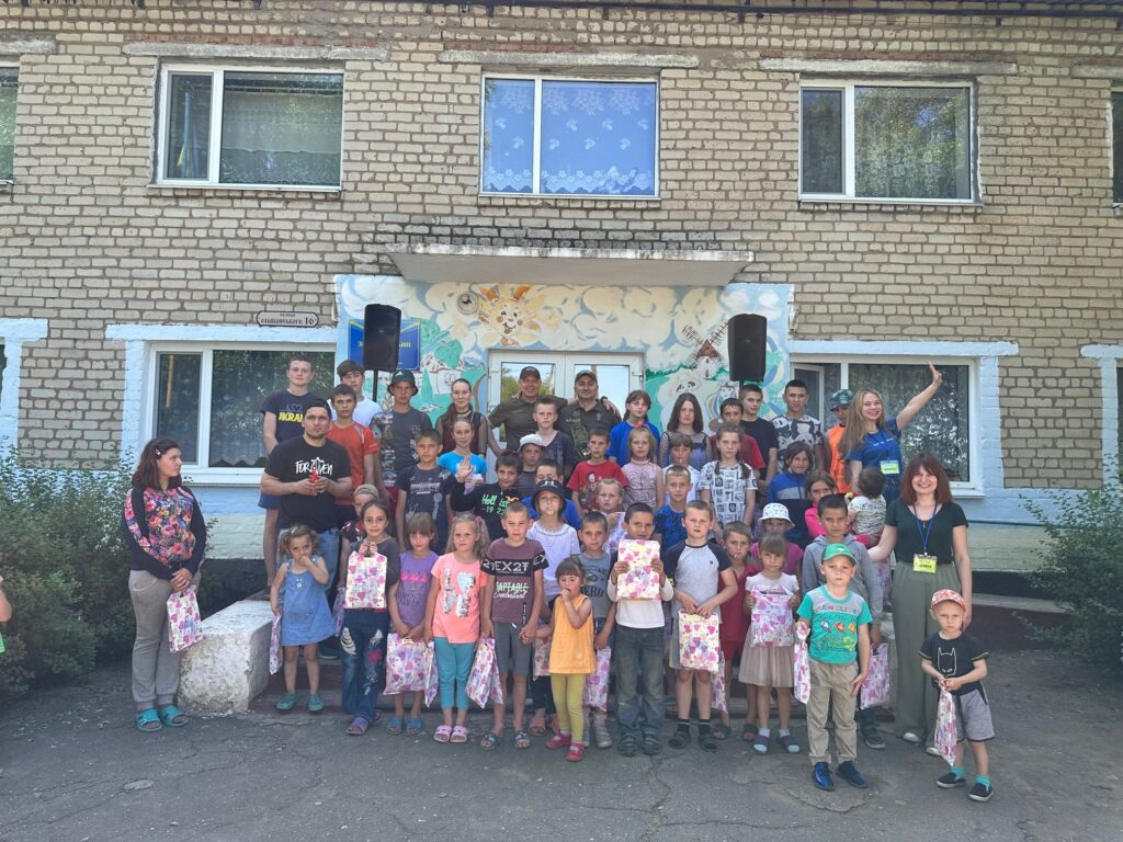 Crowd of children pose for an image in front of an all-brick building.