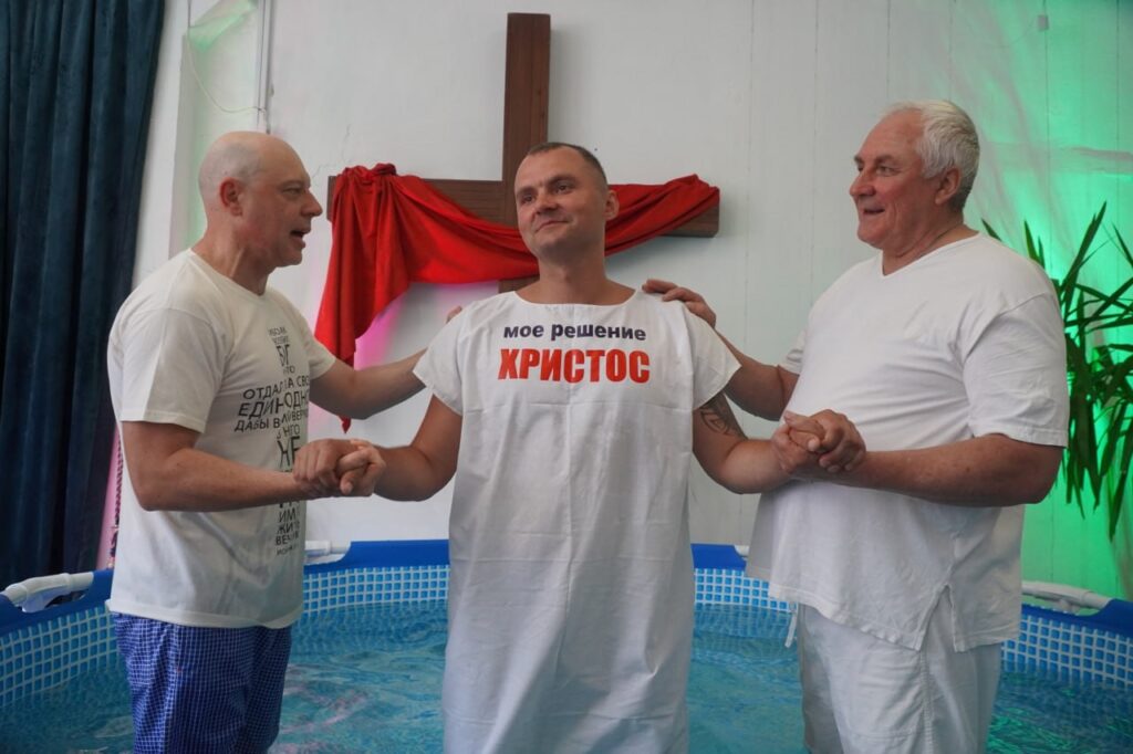 Man prepares to be water baptized by two other men.