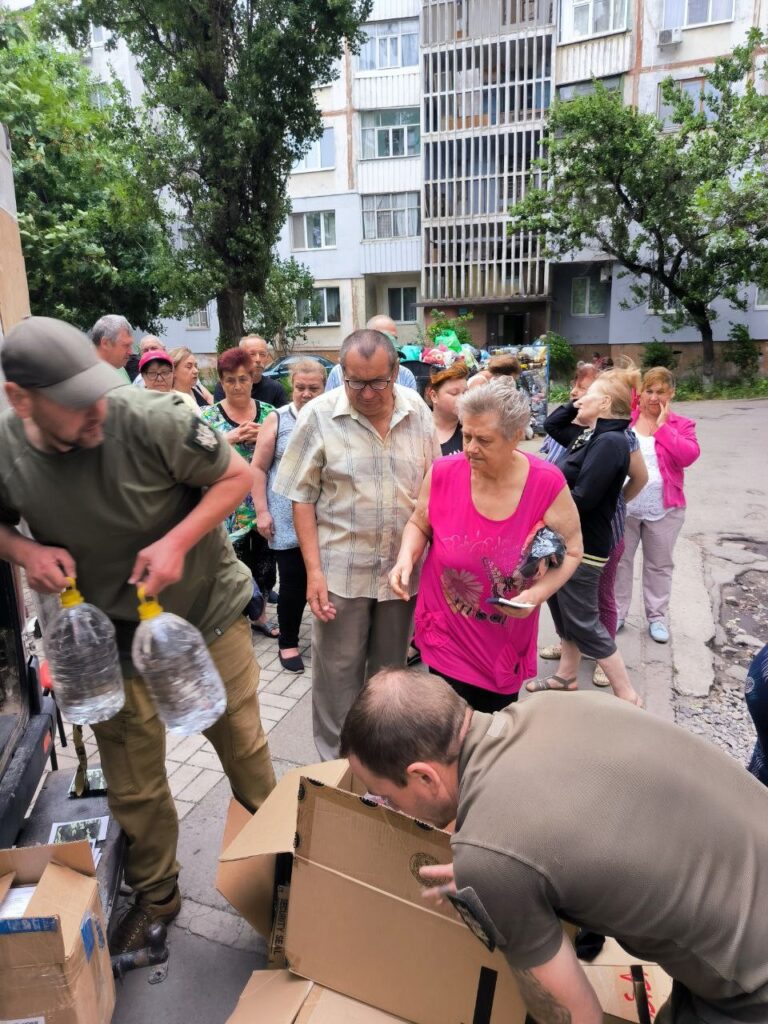 Group of Ukrainians receive supplies and water.