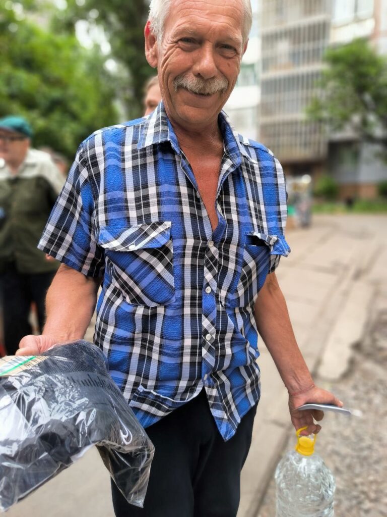 Man smiling as he receives water and supplies.