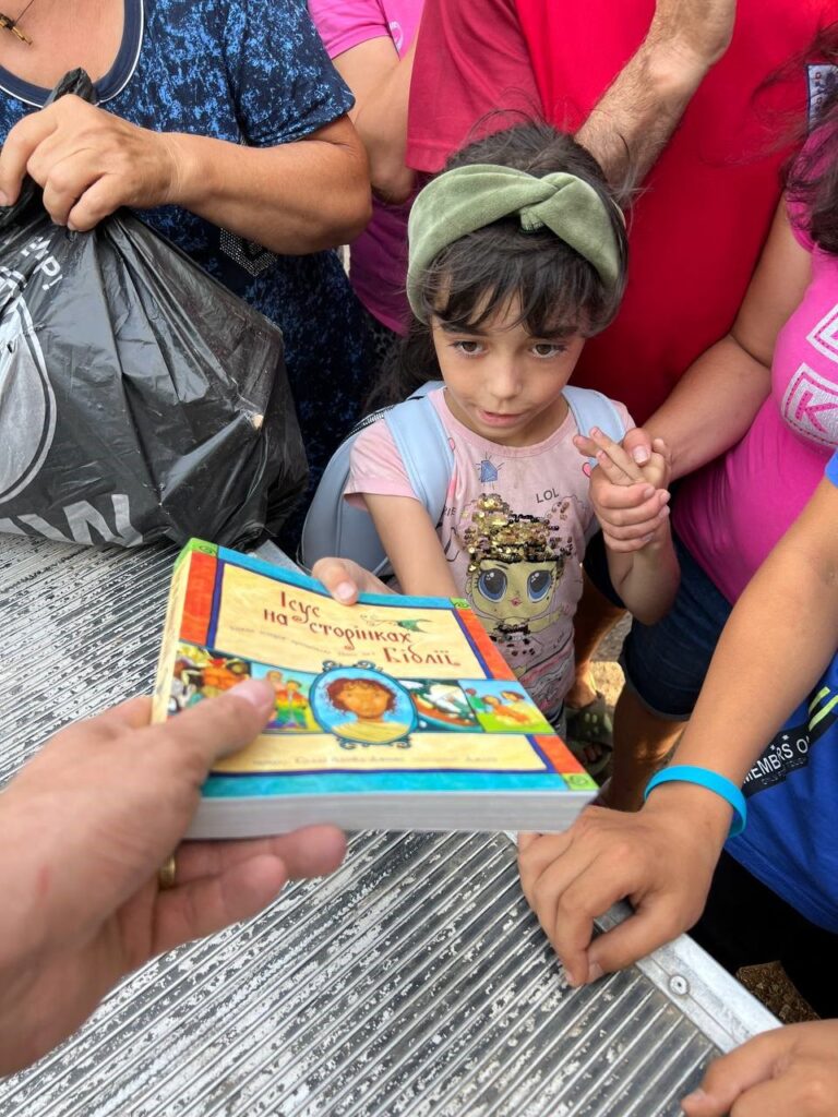 Ukrainian girl is handed children's Bible.