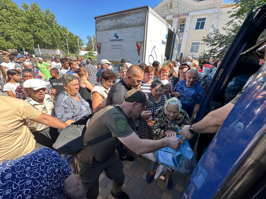 Man giving supplies to people in crowd.