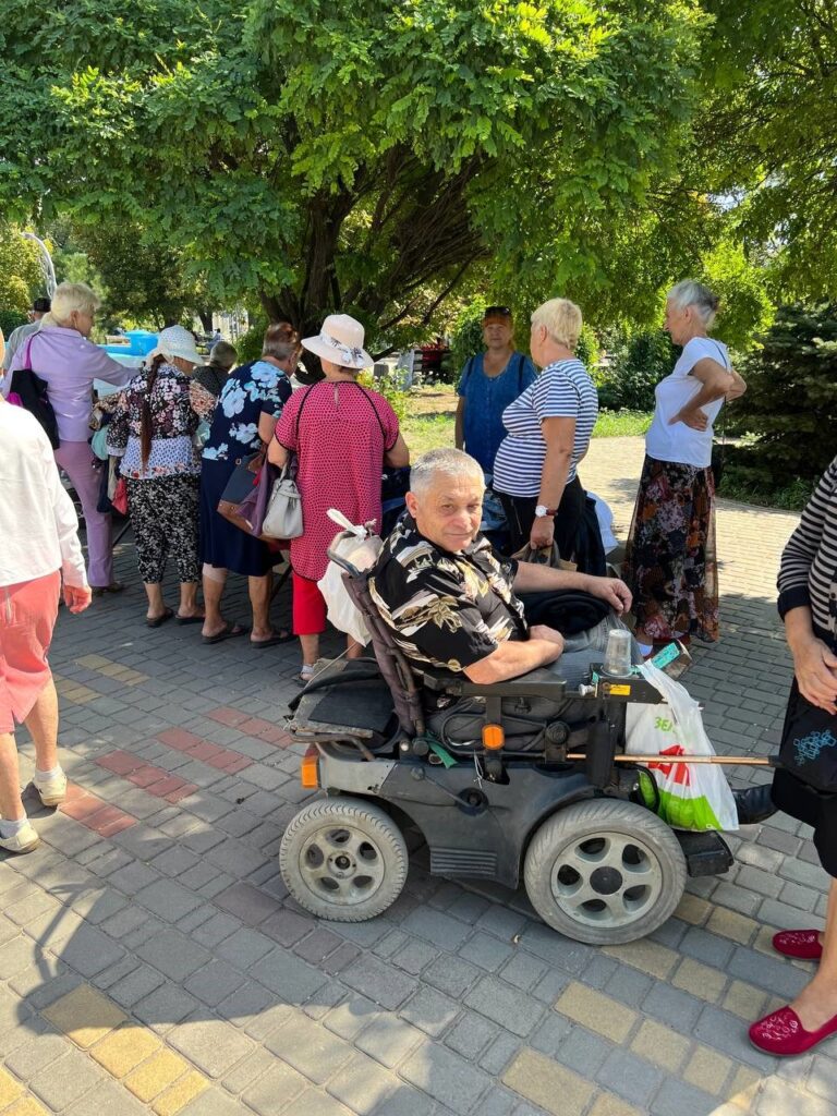 Man in wheelchair with many other people in a line behind him.