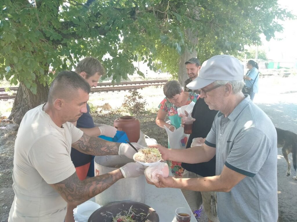 Man serving another man a bowl of food.