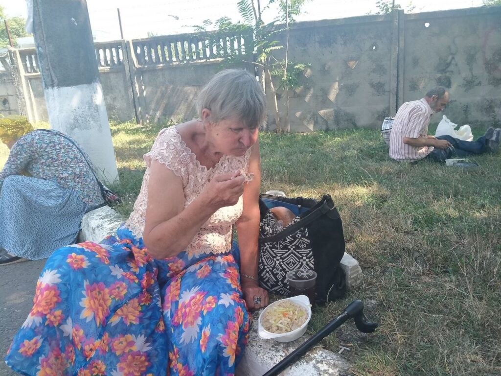 Woman sitting on the ground and eating chicken soup.