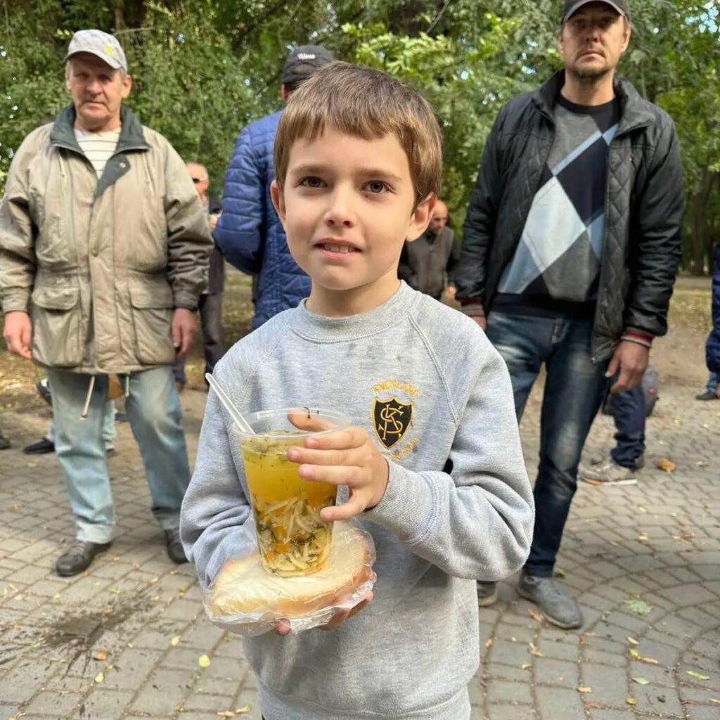 Boy holding a cup of soup and sandwich
