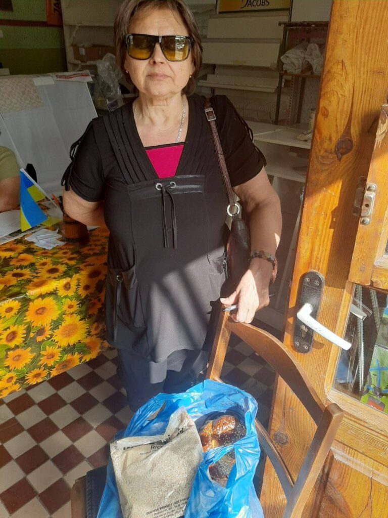 Woman next to a chair with bread and rice on a bag