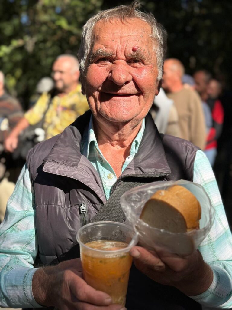 elderly man holding a cup of warm soup and a sandwich. Smiling 