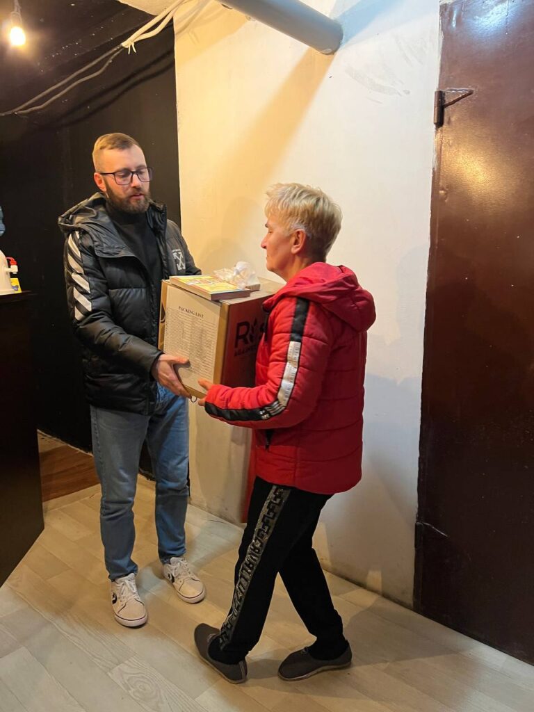 Woman in red striped jacket exchanging box with man