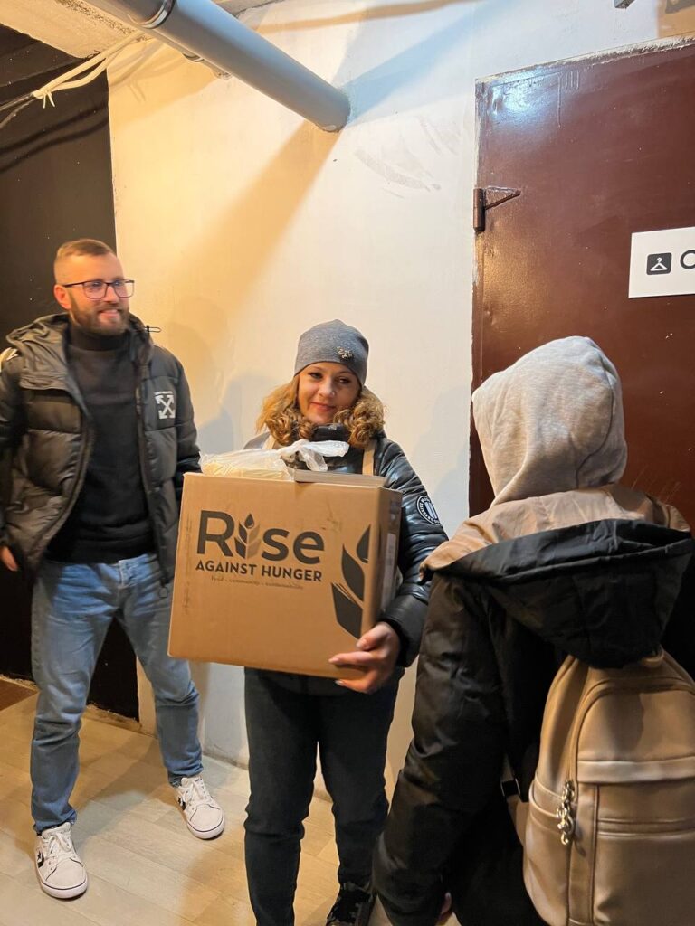 Smiling man and woman with box that says Rise Against Hunger