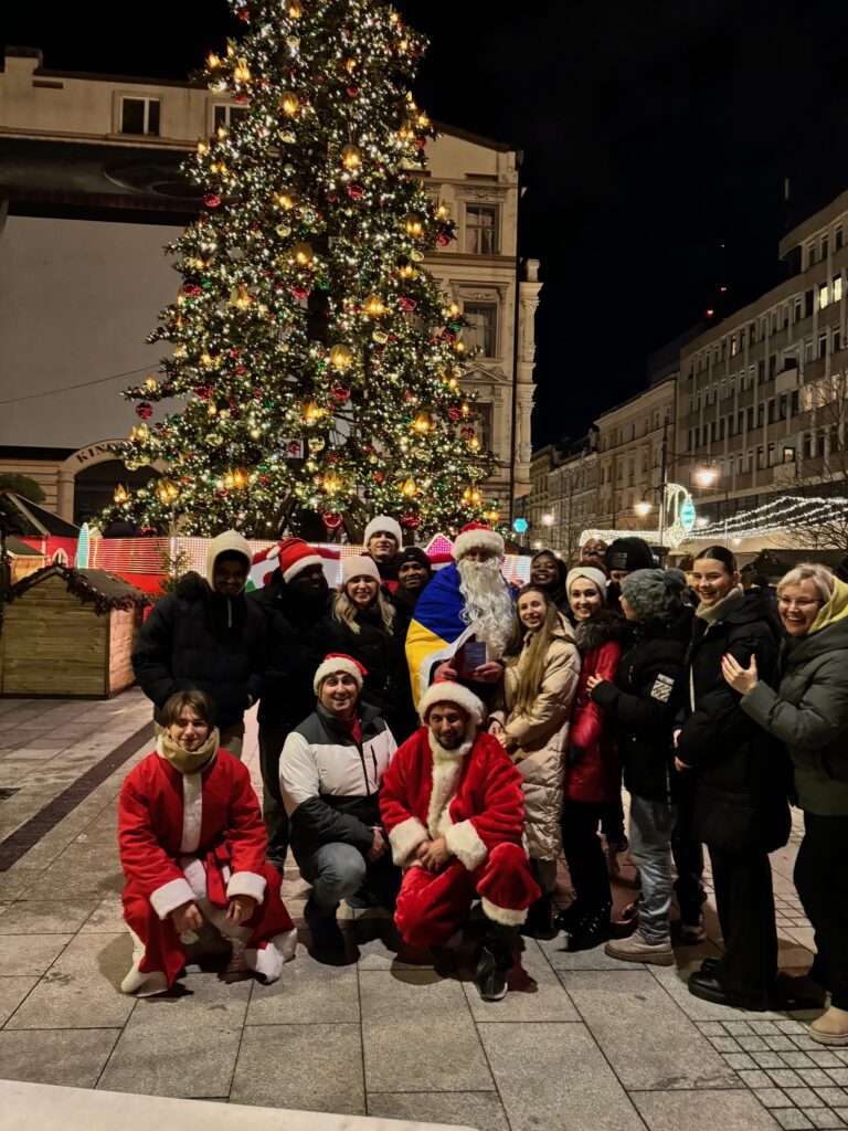 Group of people smiling at camera in front of Christmas tree