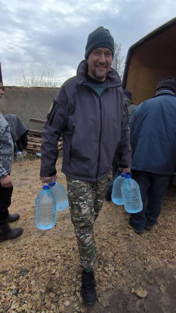 Soldier grabbing big bottles of water and walking around smiling 