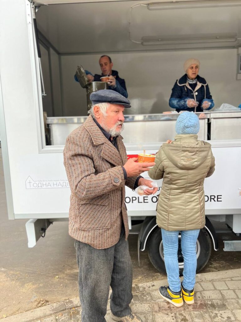 Elderly man outside of food truck holding soup