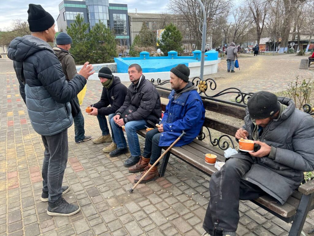 Group of men talking to each other on park bench
