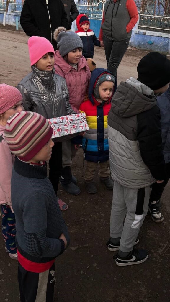 Kids gathered around, with one child holding a present.