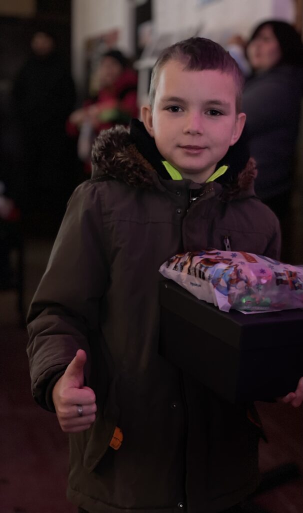 Young boy with gift and thumbs up during outreach