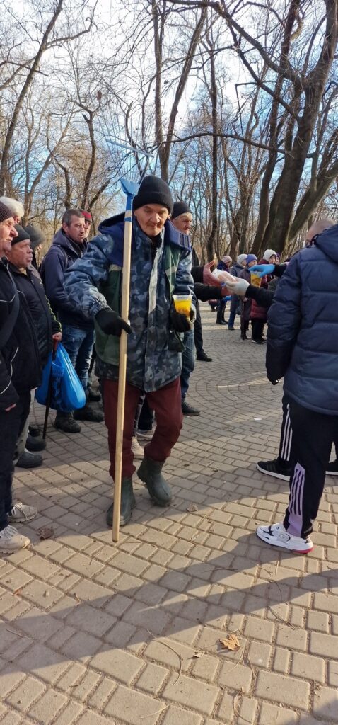 Man with a walking stick moving through a crowd.