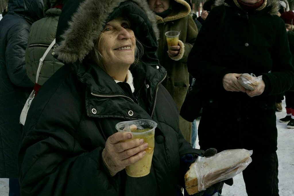 Woman smiling while holding sandwich and soup during outreach.