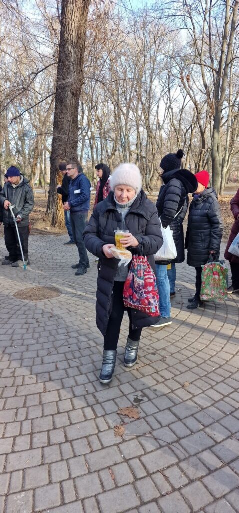 Woman walking with a juice and sandwich in hand.