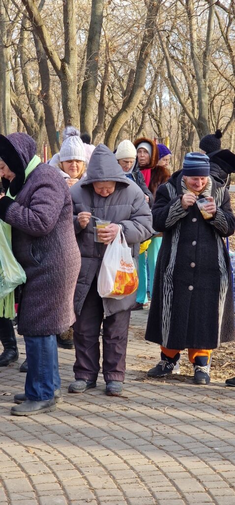 Group of women eating while standing outside in a line.