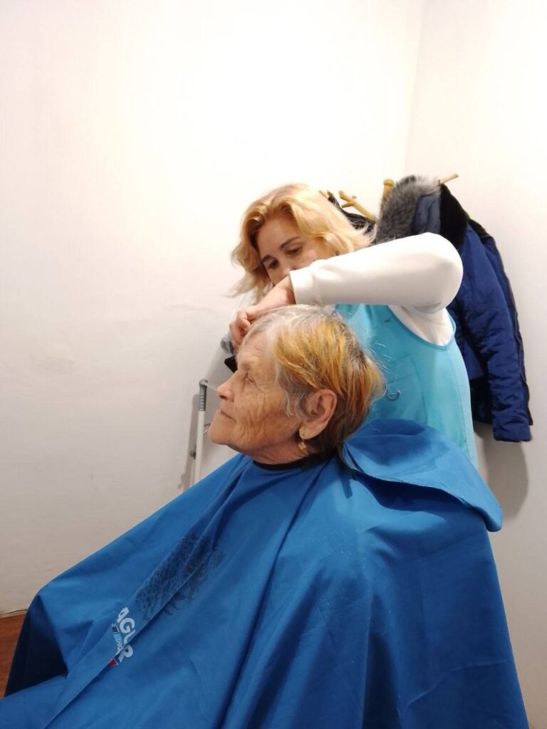 Woman giving elderly woman haircut.