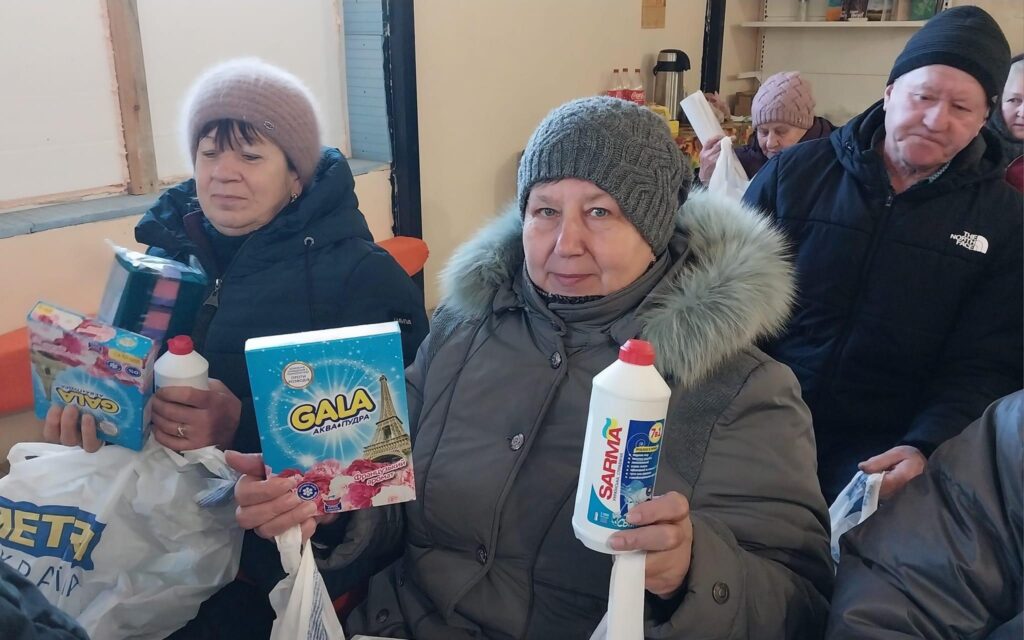 Group of people receive hygiene and cleaning supplies.