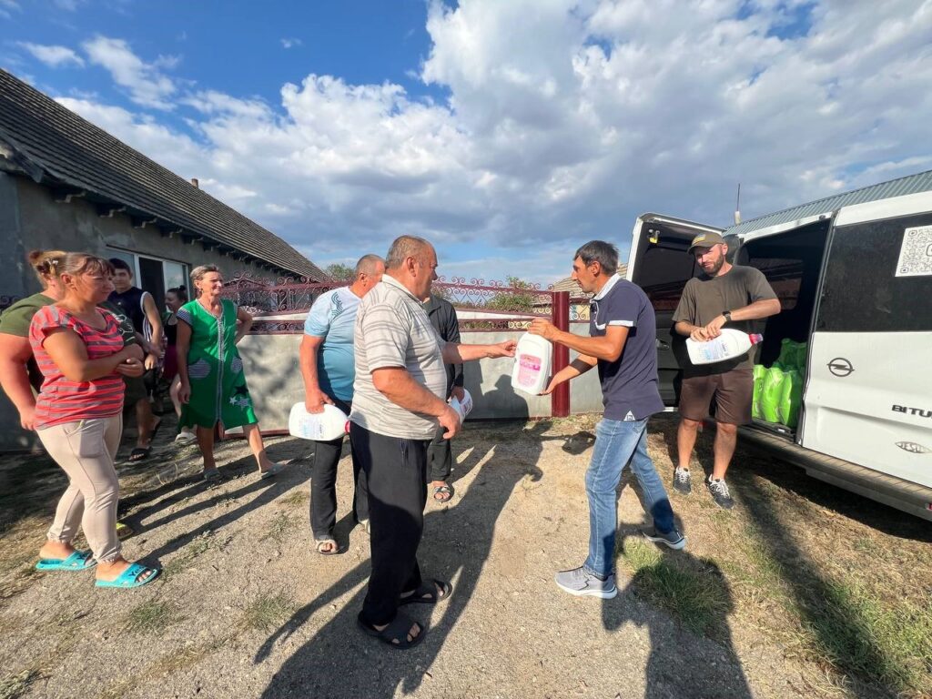 Men giving hygiene supplies to men and woman standing nearby