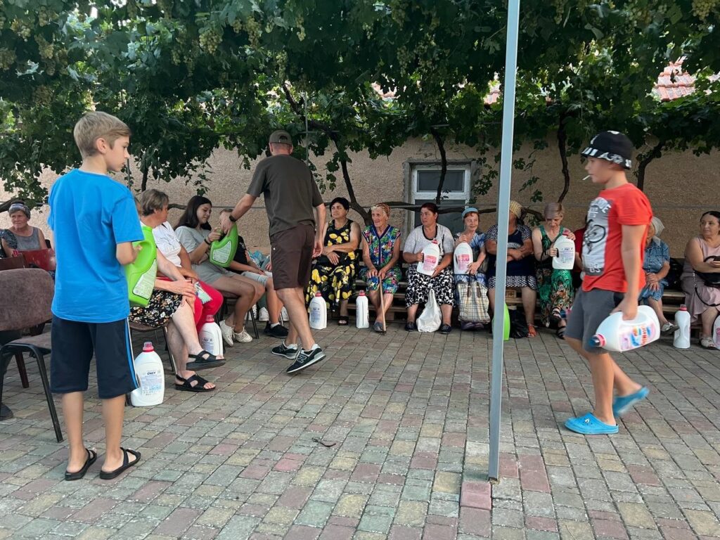 Men giving hygiene supplies to people standing nearby