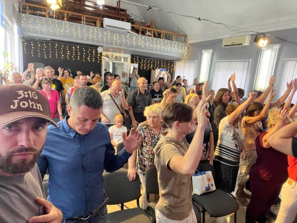 People lifting their hands in a worship service inside